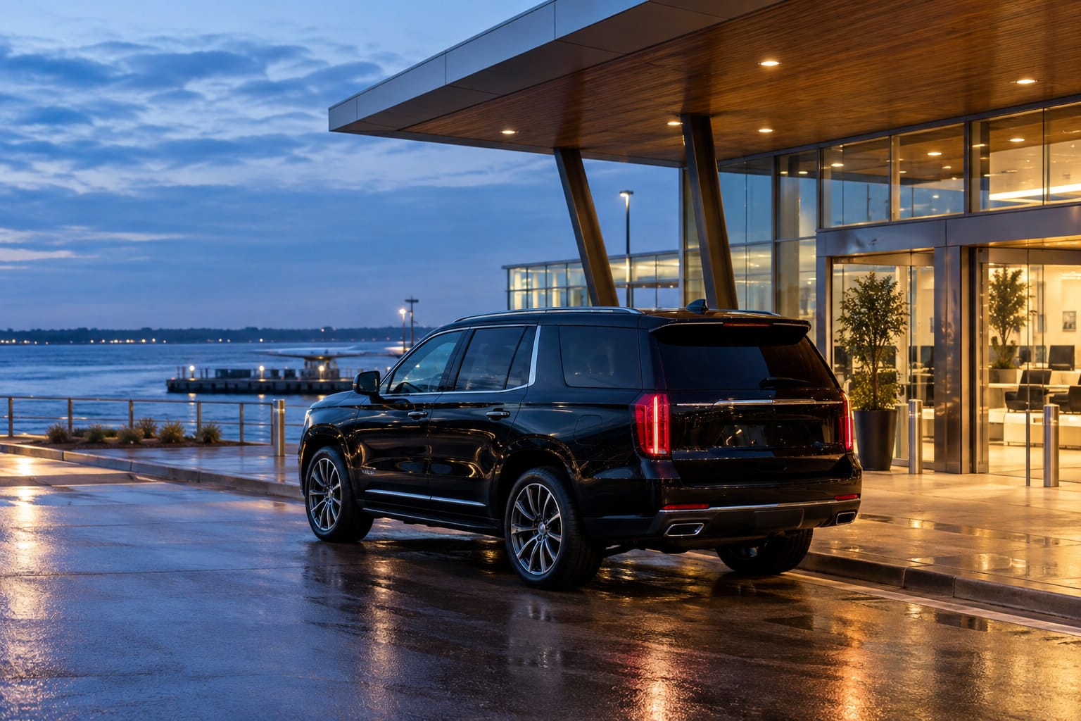 Black SUV outside a small waterfront terminal at dusk.